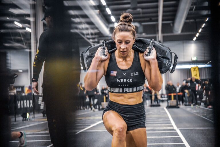 Athletin bei den Sandbag Lunges auf einem Hyrox-Event